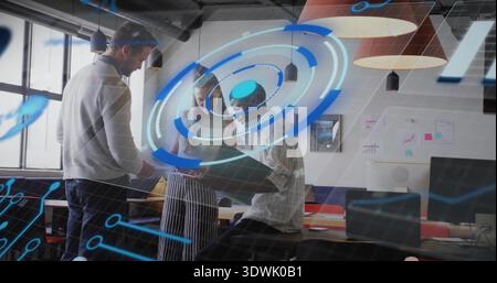 Checking three team members wearing casual, leaning over black tablet in office with AR overlay Stock Photo