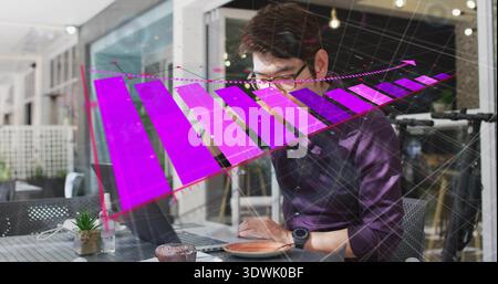 Working man in dark purple shirt typing on laptop at cafe table, showing purple bar-chart overlay Stock Photo