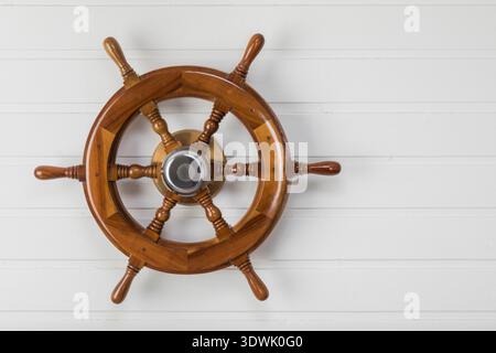 Wooden vintage boat  steering wheel mounted to white painted wall with copy space Stock Photo