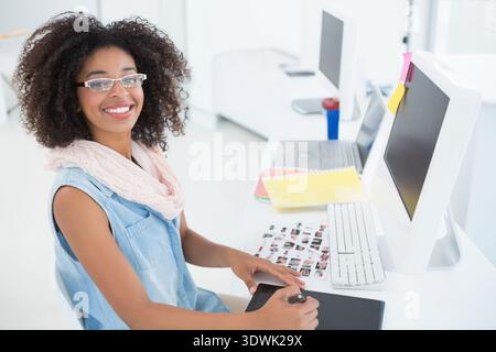 African American woman sitting at desk using stylus on graphic tablet denim pink scarf, copy space. Creative, digital, minimalist, bright, studio, wor Stock Photo