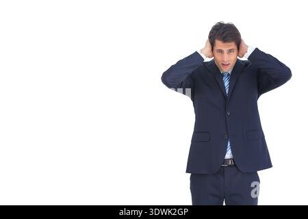 Male standing touching head on right white backdrop wearing navy suit and blue tie, copy space. Executive, studio, minimalism, corporate, headshot, co Stock Photo