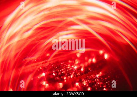 Abstract image featuring swirling red light patterns and reflections, with glimmering particles creating a vibrant and dynamic visual effect Stock Photo
