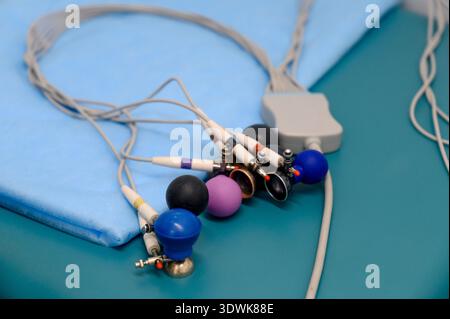 Medical electrodes with various colored connectors and cables are placed on a blue surgical table, ready for use in a clinical setting Stock Photo