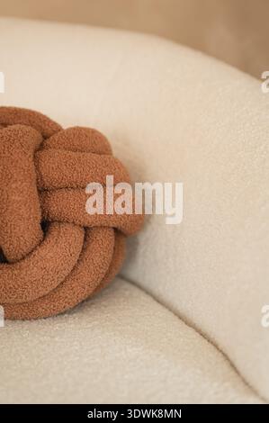 Brown knot cushion on soft beige sofa with copy space Stock Photo