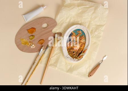 Artist palette with paint colors, brushes, and a tube of paint arranged on textured paper, showcasing tools for painting and creativity Stock Photo