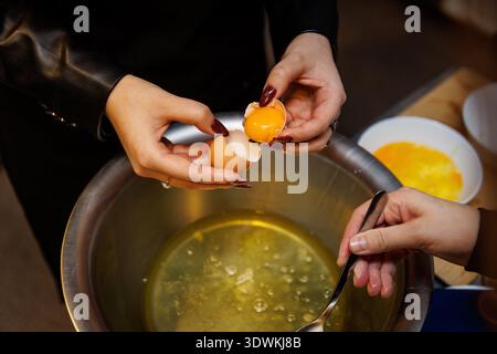 A person separates an egg yolk from the white during a professional cooking class or kitchen preparation. Stock Photo