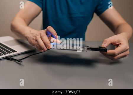 Cropped shot of male person holding external optical drive with open tray, connecting it to laptop for data storage and content access Stock Photo