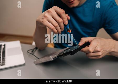 Skilled professional repairing an external optical disc drive, carefully disassembling the plastic casing with a screwdriver to reveal the internal Stock Photo