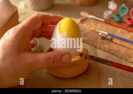 Easter DIY egg decorating process with painting tools white eggs and colorful paints in warm rustic setting Stock Photo