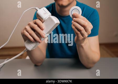 Cropped shot of person presenting innovative smart home technology, featuring power socket adapter for remote control of devices and accompanying Stock Photo