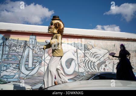 Costumed people on stilts walk past street mural Stock Photo
