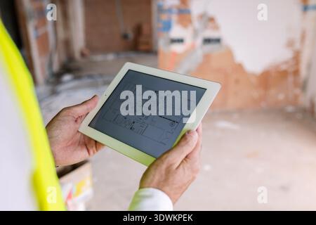 Engineer using tablet showing blueprint at construction site Stock Photo