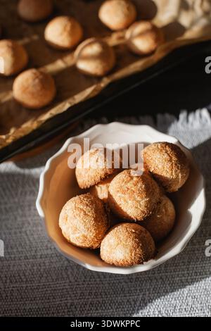 Close-up overhead view of a bowl of traditional healthy Polish coconut cookies (kokosanki) next to a baking tray of freshly baked cookies Stock Photo