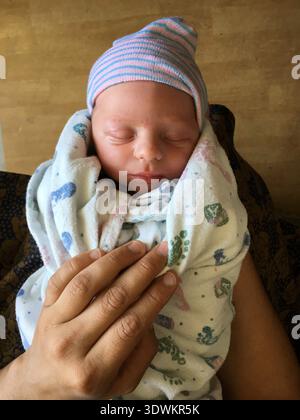 Overhead view of a newborn baby boy wrapped in a blanket on a man's lap Stock Photo