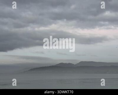 After sunset mist over the Atlantic Ocean and coastal mountains near Caminha, Viana do Castelo, Portugal, January 2024 Stock Photo