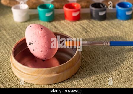 Easter egg decorating set with colorful paints brushes and pastel eggs on rustic fabric background Stock Photo