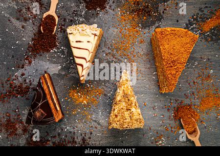 Assorted layered cake slices on dark table Stock Photo