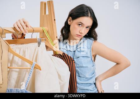 Young woman passionately works on her latest trendy collection in a bright, modern studio setting. Stock Photo