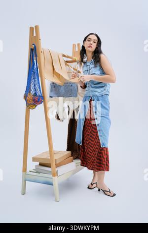 A talented young woman focuses on creating a trendy clothing line in her studio space. Stock Photo
