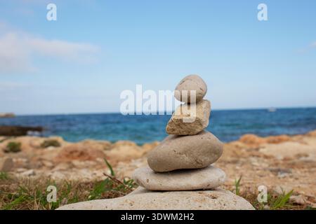 Balanced stones on pebble beach in Monopoli, Puglia, Italy. Adriatic sea background. Stock Photo