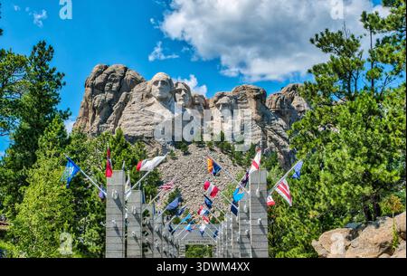 A large crowd of people are gathered in front of the Washington Monument. The monument is surrounded by flags from various countries, and the sky is c Stock Photo