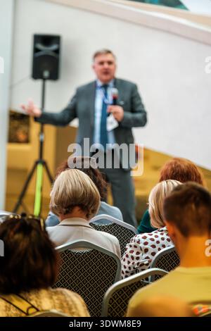 Business speaker presents to attentive audience at conference, professional seminar atmosphere, networking, learning, engagement. Stock Photo