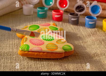 Easter gingerbread cookies in bunny shape being decorated with colorful icing at home Stock Photo