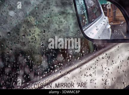 A view of a car sideview mirror in the rain Stock Photo