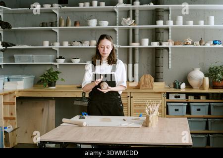 Young Adult Woman Shaping Clay While Working in Ceramics Studio Stock Photo