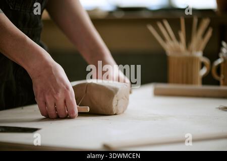 Woman Shaping Clay with Wooden Tool in Pottery Studio Stock Photo