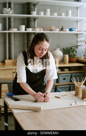 Young Adult Woman Shaping Clay While Working in Creative Studio Stock Photo