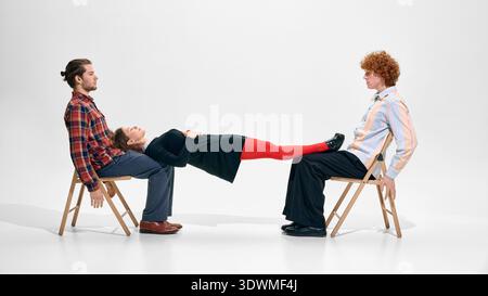 Three colleagues seated in dynamic fashion inspired studio composition on white background. Stock Photo