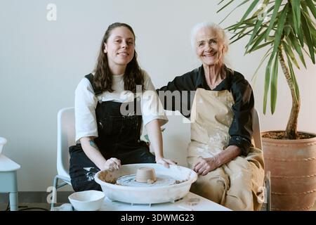 Young Adult Woman and Senior Woman Creating Pottery Together Stock Photo