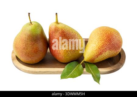 Three whole fresh ripe red yellow pear fruits with green leaves on wooden plate tray closeup isolated on white background. Healthy food. Stock Photo