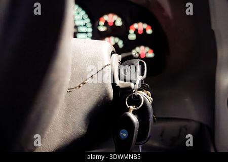 Close-up of car keys in ignition with illuminated dashboard gauges, showing Chevrolet logo Stock Photo