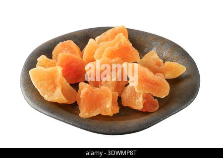 Candied melon pieces with sugar in dark vintage plate closeup isolated on white background. Healthy dessert with fiber and vitamin. Stock Photo