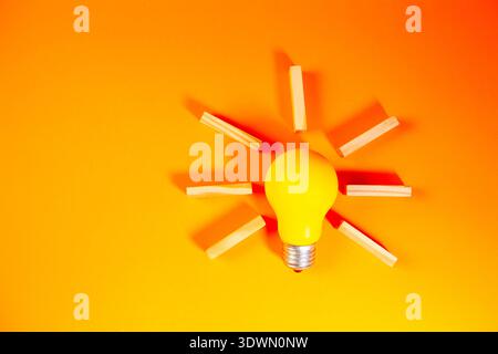 Light bulb with wooden matches on orange background. Concept of idea. Stock Photo
