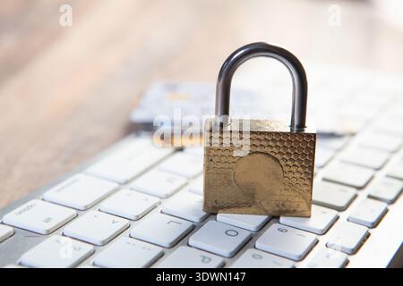 Padlock on computer keyboard with credit card on wood table background. Stock Photo