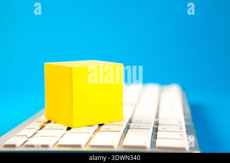 yellow cube on a white keyboard on a blue background, business concept Stock Photo