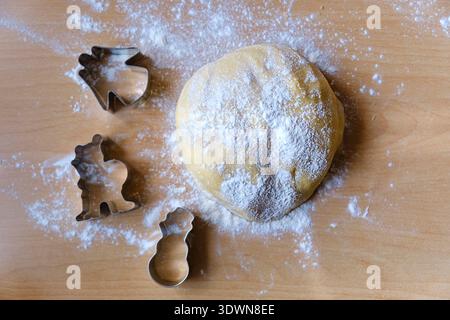 Floured cookie dough with baking molds on rustic wooden table. Cozy homemade baking and family kitchen atmosphere. Stock Photo