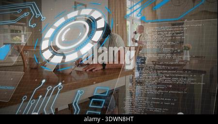 Writing mature man sitting at dining table at home, holding pen with AR HUD overlays Stock Photo