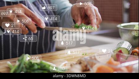 Chopping senior woman in striped apron preparing produce on board in kitchen, chef's knife overlays Stock Photo