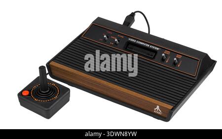 An Atari 2600 four-switch wood veneer model, dating from the early 1980s (circa 1980-1982), is displayed with its classic joystick. This iconic video computer system represents a significant piece of video game history, embodying the dawn of home console gaming. Stock Photo