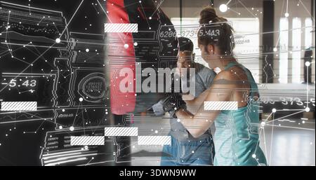 Training coach in shirt guiding student in teal tank punching red-black bag at gym, HUD-graphics Stock Photo