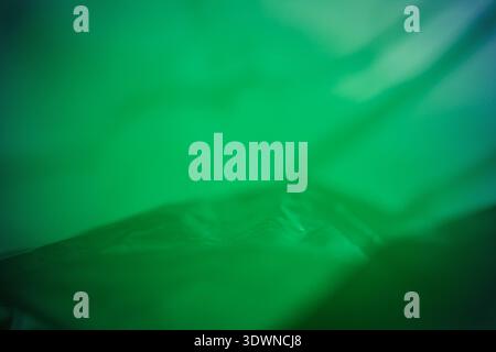 Extreme close up of green empty plastic bag background. The plastic surface is wrinkly and tattered making abstract pattern. Selective focus, shallow Stock Photo