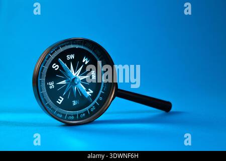 Compass and magnifying glass on blue background. Travel and navigation concept. Stock Photo