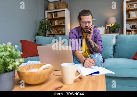 Freelance AI consultant working from home on sofa, smiling during phone call while reviewing analytics reports on laptop, remote technology advisory a Stock Photo