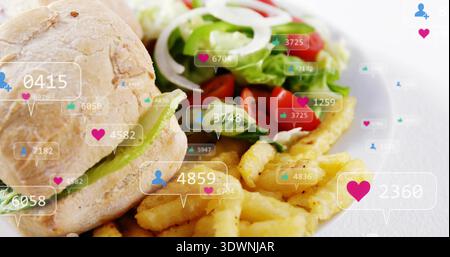 Displaying plated lunch on white tabletop, sandwich roll with lettuce, fries, salad, overlay badges Stock Photo