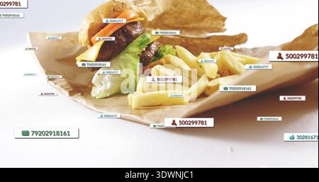 Displaying double-patty burger and fries on white tabletop over brown paper, with digital tags Stock Photo