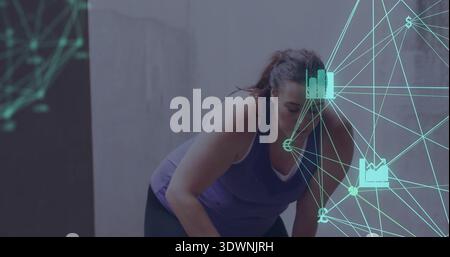 Leaning woman in purple tank, dark leggings, pausing at concrete wall panel with teal network icons Stock Photo